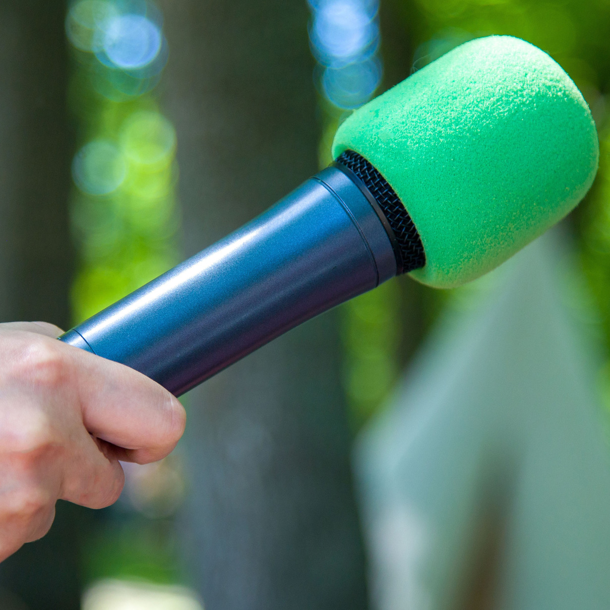 Eine Hand hält ein grünes Mikrofon